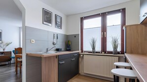 Una cocina moderna con isla integrada, comedor con mesa y sillas de madera, y ventana con persianas.