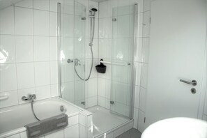 Un baño moderno con ducha envuelta en vidrio, una bañera y un inodoro.