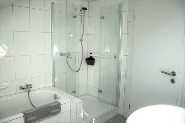 Une salle de bain moderne dotée d’une douche à parois de verre, d’une baignoire et de toilettes.