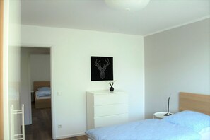 A bedroom with a bed, a dresser, a bedside table, and a wall-mounted picture. - Apartment 'Wahl' with Mountain View, Balcony and Wi-Fi (Schmallenberg)