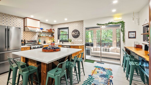 Een moderne keuken met een centraal eiland, barkrukken en een eethoek met uitzicht op de omgeving.