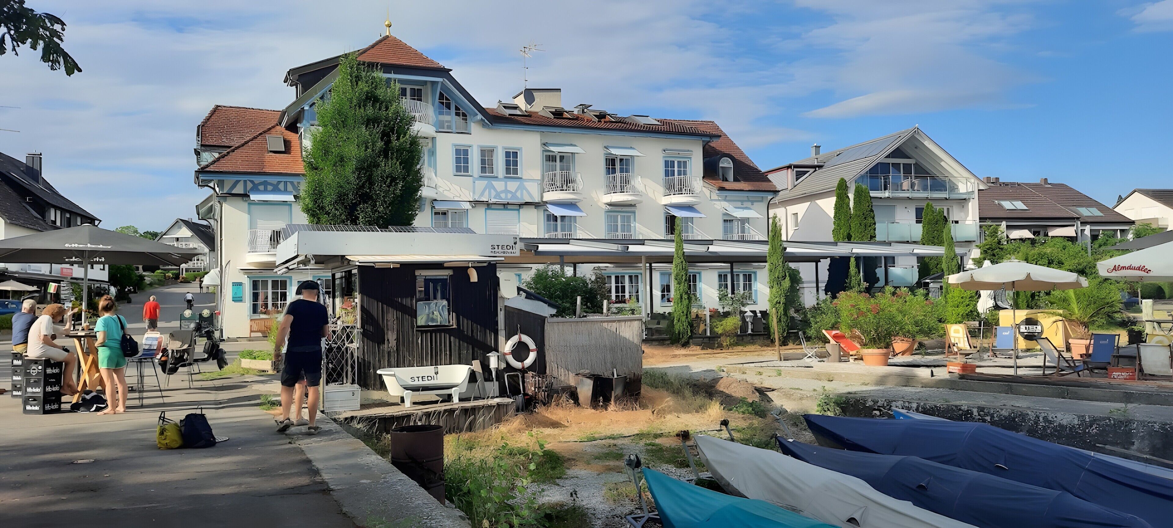 A riverside building with a dock, boats, and outdoor seating.