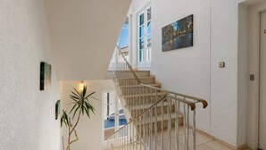 A staircase with a handrail, a potted plant, and a painting on the wall. - Room '2 Bett Ohne Seeblick' with Shared Terrace, Balcony and Wi-Fi (Reichenau)