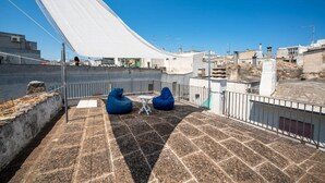 A rooftop terrace with two blue bean bags, a small table, and a white canopy.