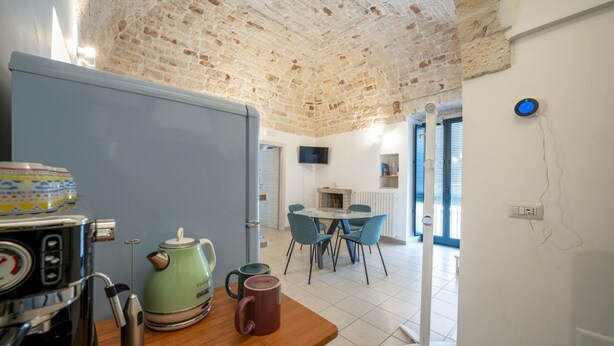 A kitchen with a brick ceiling, a coffee machine, a kettle, and a table with chairs.