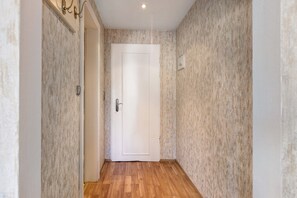 A narrow hallway with a wooden floor, a white door, and textured walls.