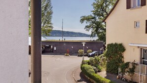 A building with a parking area, a view of the sea, and a hillside in the background. - Room '2-Bett Ohne Seeblick' with Shared Terrace, Balcony and Wi-Fi (Reichenau)