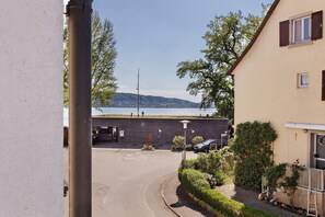 A building with a parking area, a view of the sea, and a hillside in the background.