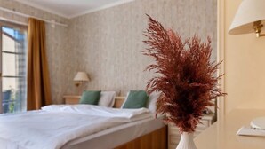 A hotel room with a bed, a nightstand, and a white vase with a plant. - Room '2-Bett Ohne Seeblick' with Shared Terrace, Balcony and Wi-Fi (Reichenau)