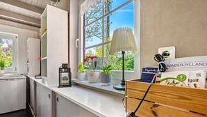 Een moderne keuken met een raam, witte kasten, een houten aanrecht en potplanten.
