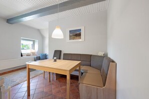 Un interno moderno con un tavolo in legno, una panca imbottita, un quadro appeso al muro e una finestra vista.