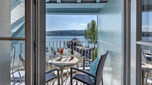 A balcony with a table, chairs, and a bottle of wine, overlooking a body of water and a dock. - Room 'Suite Mit Seeblick U Balkon' with Lake View, Shared Terrace and Wi-Fi (Reichenau)