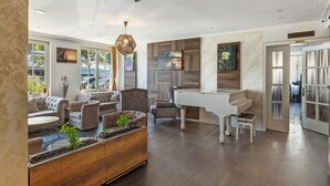 A spacious living area with a grand piano, comfortable seating, and a large window. - Room 'Suite Mit Seeblick U Balkon' with Lake View, Shared Terrace and Wi-Fi (Reichenau)