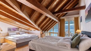 A bedroom with a sloped ceiling, two beds, a window with curtains, and a view of the outdoors. - Room 'Suite Mit Seeblick U Balkon' with Lake View, Shared Terrace and Wi-Fi (Reichenau)