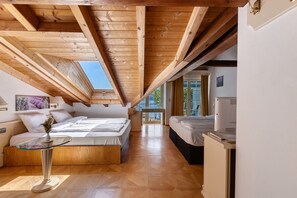 A bedroom with a skylight, wooden beams, a bed, a bedside table, and a view of the outdoors.