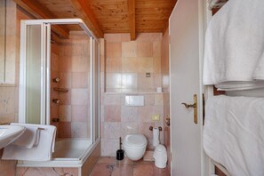 A bathroom with a shower, toilet, sink, and towel rack.