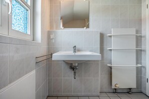 A bathroom with a white sink, mirror, and towel rack.