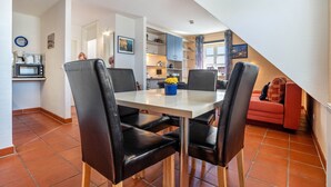Comedor con mesa, sillas y cocina al fondo.