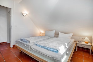 Une chambre à coucher comprenant un lit, une table de chevet, une lampe et un luminaire fixé au mur.