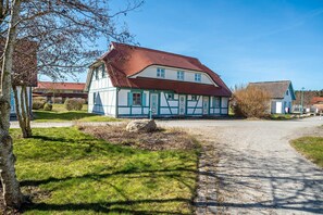 A traditional half-timbered house with a red roof, a gravel driveway, and a well-maintained lawn.