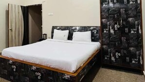 Une chambre à coucher comprenant un lit, un ventilateur de plafond, une armoire et un mur orné d’un motif décoratif.