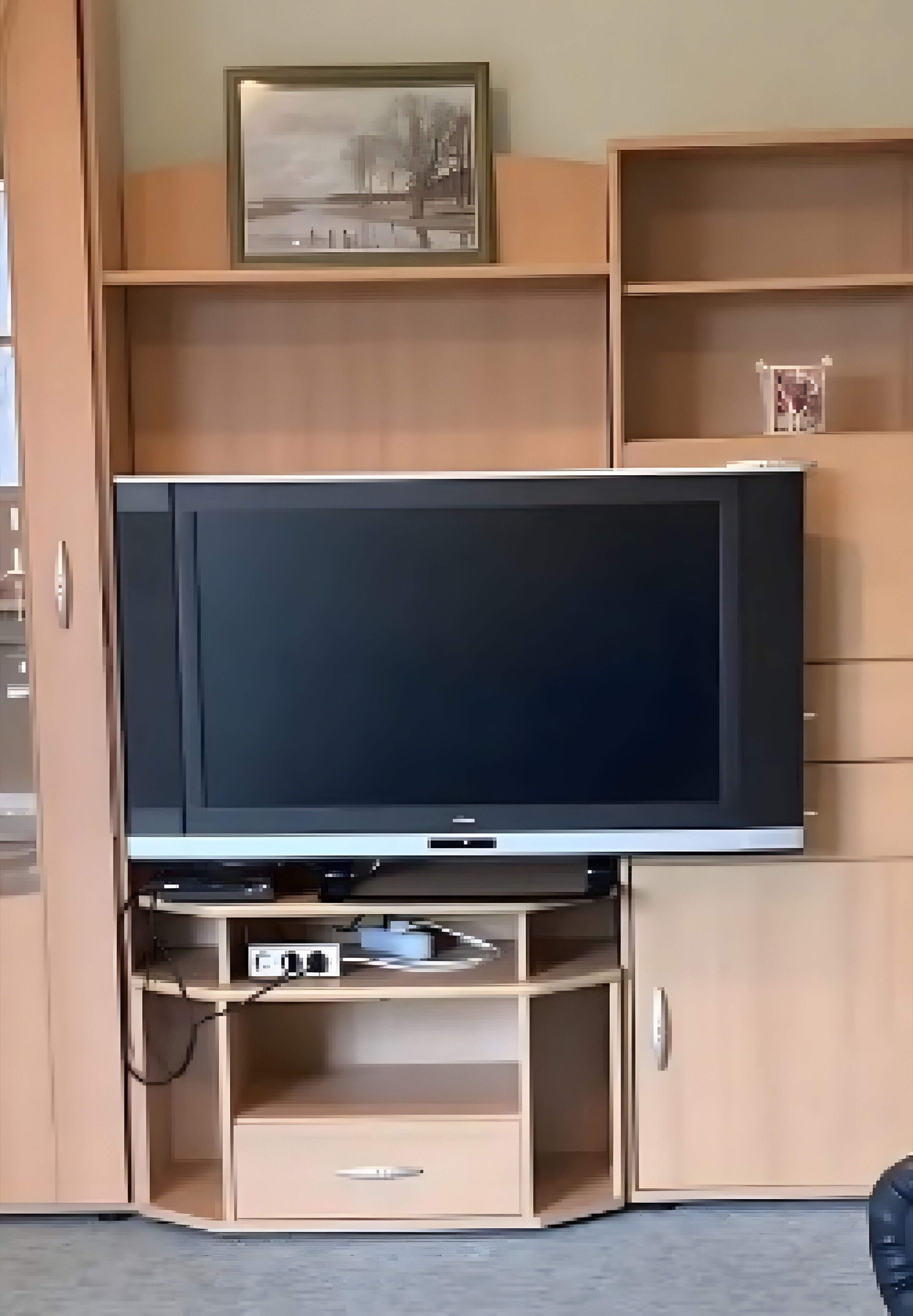 Un téléviseur posé sur un meuble bas en bois, avec un cadre photo au-dessus.