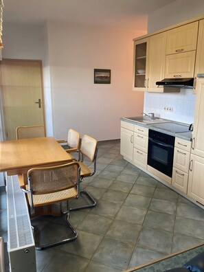 A kitchen with a dining table, chairs, a stove, and cabinets.