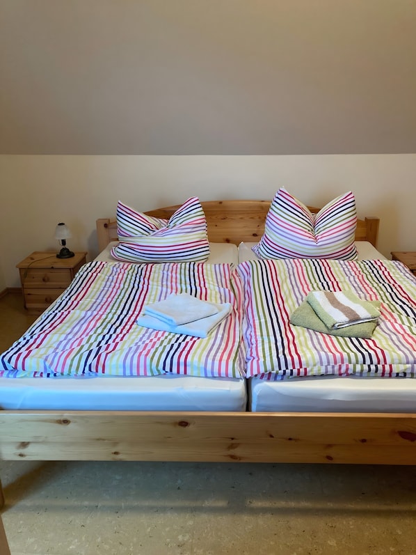 A double bed with striped bedding, two pillows, a bedside lamp, and a wooden headboard.