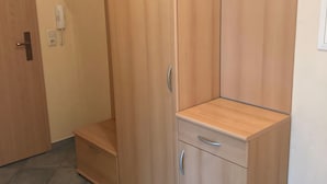 Huoneessa on puinen vaatekaappi, ovi ja seinälle asennettu puhelin.