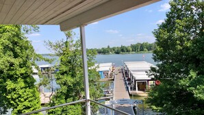 Un port de plaisance avec des bateaux amarrés, une terrasse en bois et une vue sur le lac.