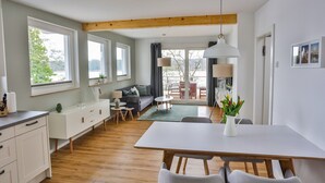 Une cuisine moderne avec des meubles blancs, une table à manger en bois et une grande fenêtre.