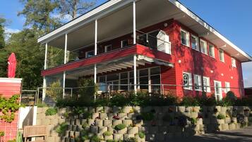 A red building with a balcony, a covered porch, and a flower wall.