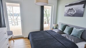 Une chambre à coucher avec un lit, une commode, une table de chevet, une lampe et un tableau.