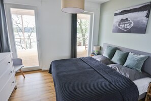 A bedroom with a bed, a dresser, a nightstand, a lamp, and a painting.