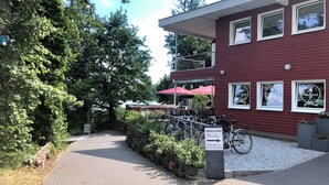 Un bâtiment rouge avec de nombreuses fenêtres, un chemin pavé et des vélos garés devant.