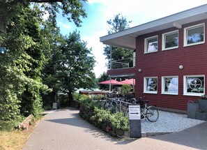 A red building with multiple windows, a paved pathway, and bicycles parked in front.