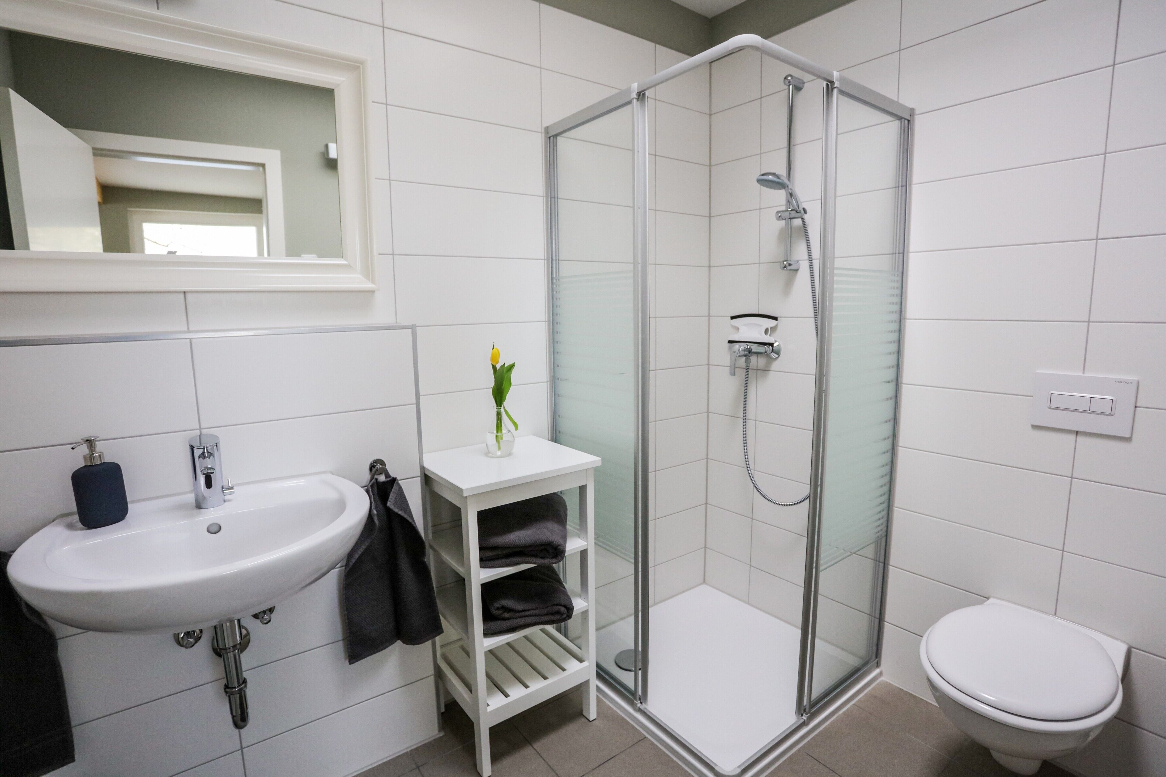 Une salle de bain avec un lavabo blanc, une douche à parois de verre et des toilettes blanches.