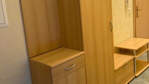 Une chambre avec une armoire en bois, un petit bureau et un téléphone.