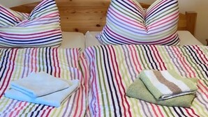 Un lit double avec une literie à rayures et des oreillers, une tête de lit en bois et une serviette pliée posée sur le lit.