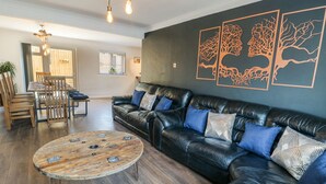 Ein modernes Wohnzimmer mit einer Ledersofa, einem Holztisch und einem Essbereich mit einem Holztisch und Stühlen.