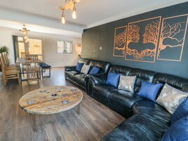 A modern living room with a leather sofa, a wooden coffee table, and a dining area with a wooden table and chairs.