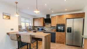 Eine moderne Küche mit Holztisch und Barhocker, Edelstahlgeräten und einem eingebauten Backofen.