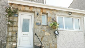 Ein Steinhaus mit einer weißen Tür, Hausnummer 28, und einem kleinen Fenster darüber.