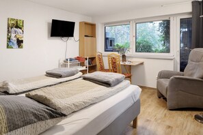 A hotel room with a bed, a chair, a desk with a plant, and a TV on the wall. - Apartment 'Tuniberg' with Wi-Fi (Umkirch)