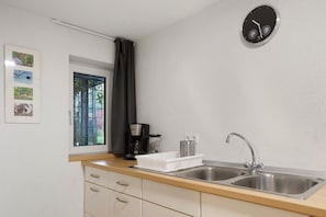 A kitchen with two sinks, a coffee maker, a window with a view, and a clock on the wall. - Apartment 'Tuniberg' with Wi-Fi (Umkirch)