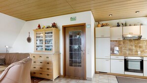 Een keuken met houten kastjes, een fornuis en een eethoek met een bank.