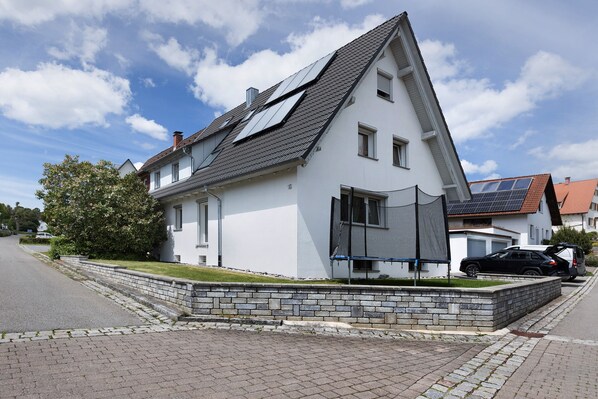 A modern house with a sloped roof, solar panels, and a paved driveway.