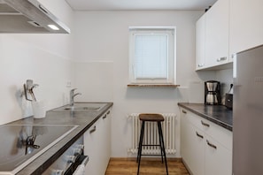 Eine moderne Küche mit Arbeitsplatte, Spüle, Herd und einem Fenster mit Jalousien.
