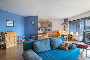 Un soggiorno con un divano blu, una cassettiera in legno e un'area pranzo con tavolo e sedie.