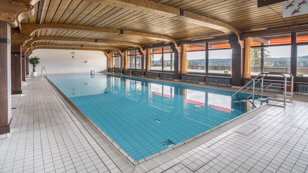 An indoor swimming pool with wooden beams, tiled floor, and large windows. - Apartment 'Terrassenpark 160' with Mountain View, Balcony and Wi-Fi (Schonach)